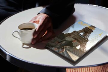 OutThere Paris is turning issue on a table while man holds coffee cup