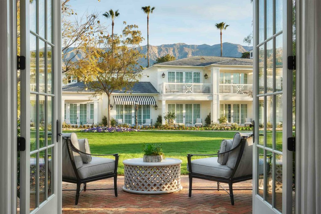 A suite patio with chairs before a white mansion at Rosewood Miramar Beach.