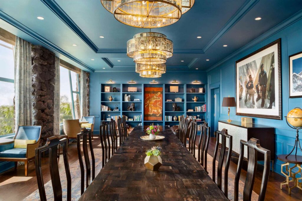 A stylish dining space with a large wooden table and blue walls and ceiling.