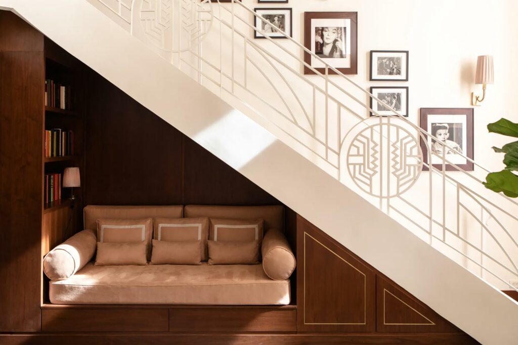 A banquette under a staircase with vintage photos on the wall.