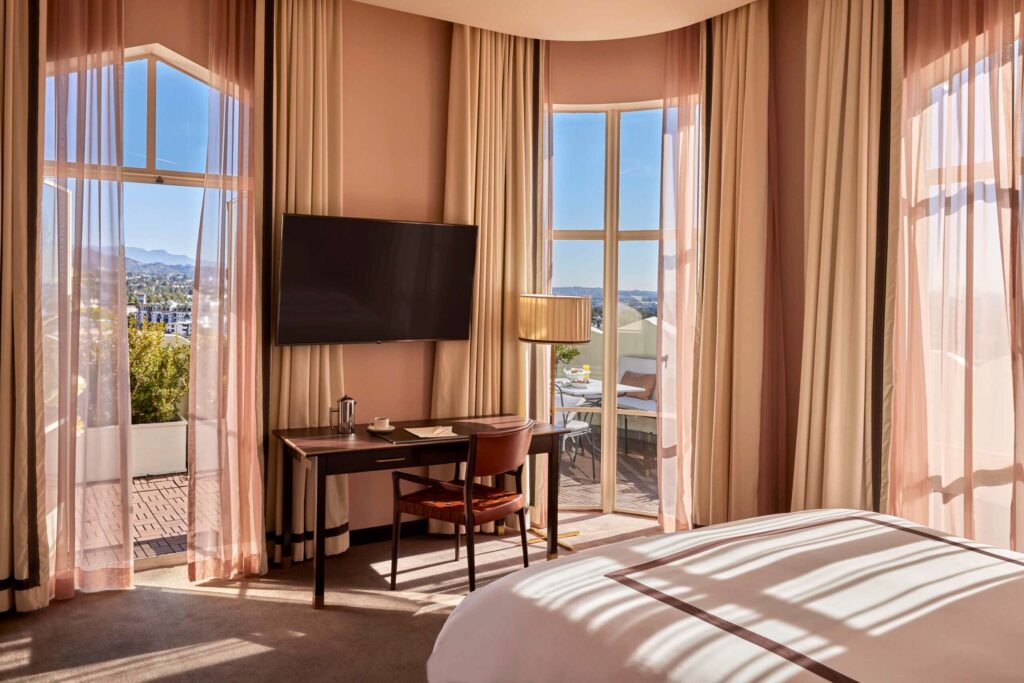 A brightly lit bedroom with views of West Hollywood at Sunset Tower Hotel.