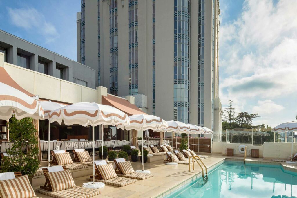 An outdoor terrace with a pool and white umbrellas at Sunset Tower Hotel.