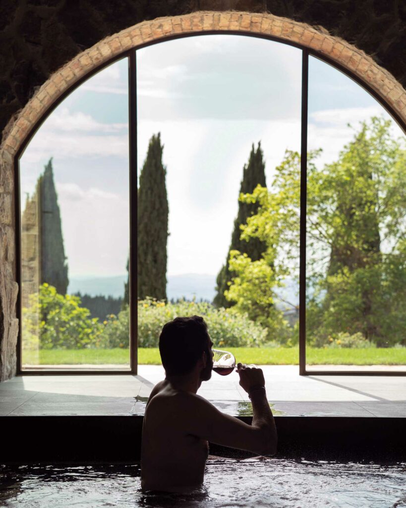 A guest enjoys a glass of wine in a pool at Villa Ardore, Tuscany, Italy