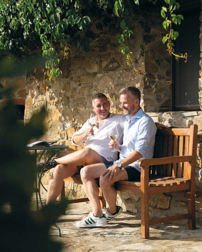 Stephen Lewis and Christian Scali enjoy a glass of wine on a bench at Villa Ardore, Tuscany, Italy