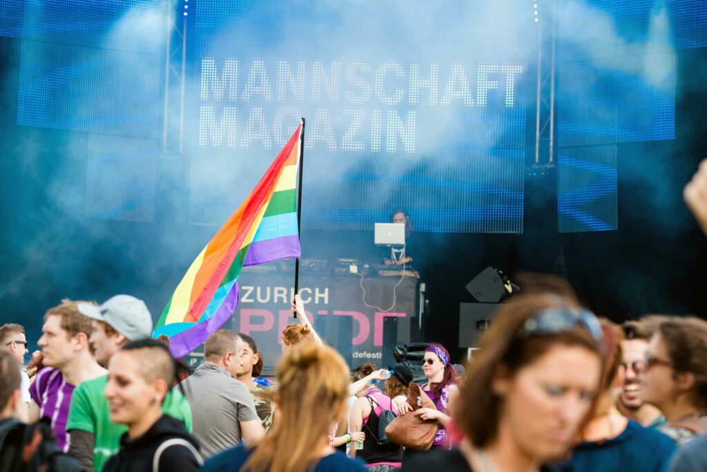 A rainbow flag is waved in front of a stage at Zurich Pride, Switzerland