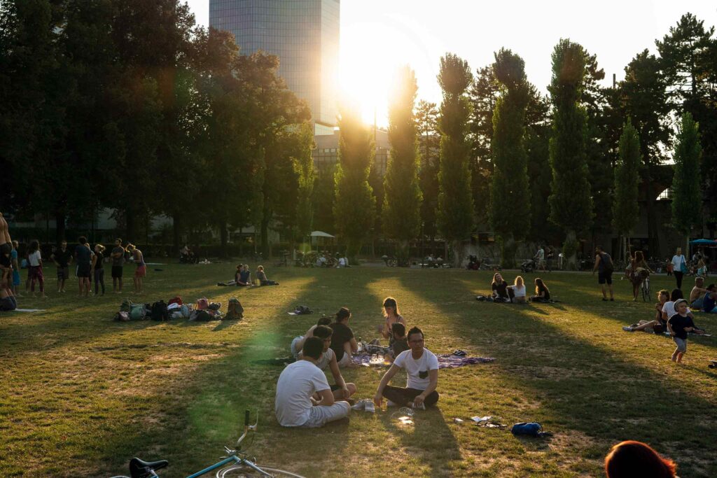 Locals enjoy the sunshine sitting in a a park in Zurich West, Zurich, Switzerland