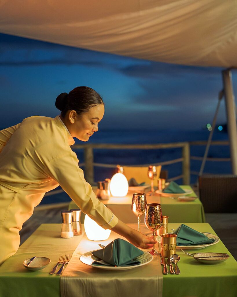 A waitress sets a table at Atmosphere Kanifushi, Maldives