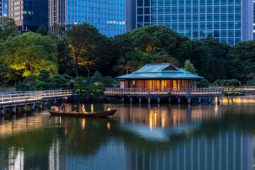 Boatman and geisha rowing boat on lake to backdrop of skyscrapers in Tokyo