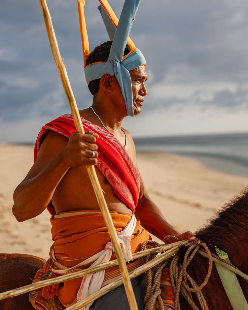 A local man from Sumba, Indonesia rides a horse on the beach