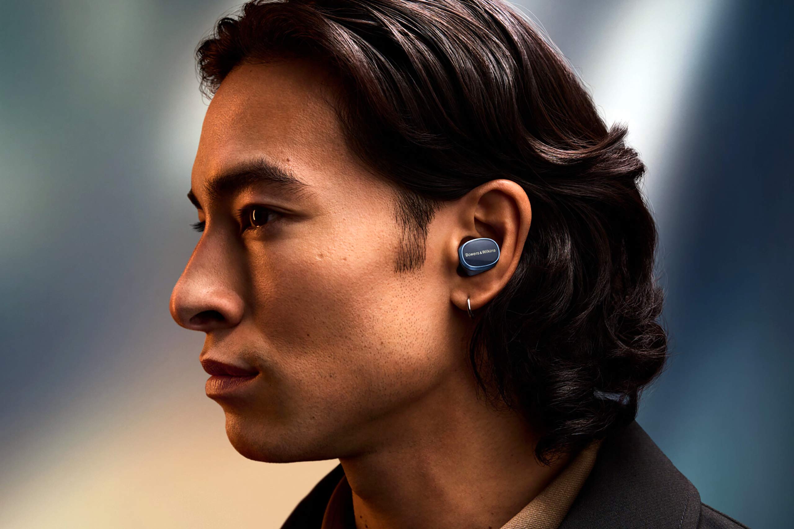 A model wears the Bowers & Wilkins In-Ear True Wireless Earbuds, part of the OutThere travel gadgets gift guide 2024