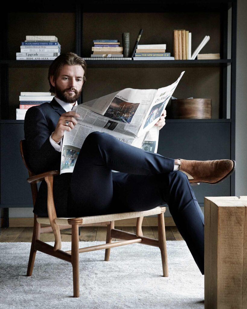 A man dressed in a suite reads a newspaper in Ålesund, Norway