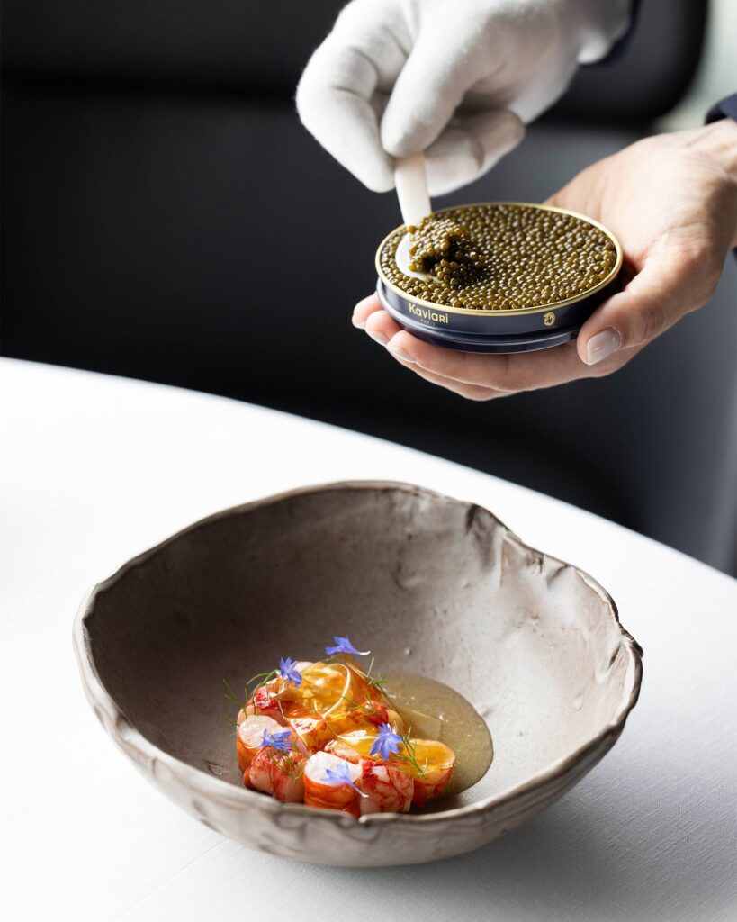 Caviar being spooned onto an artfully presented plate of food