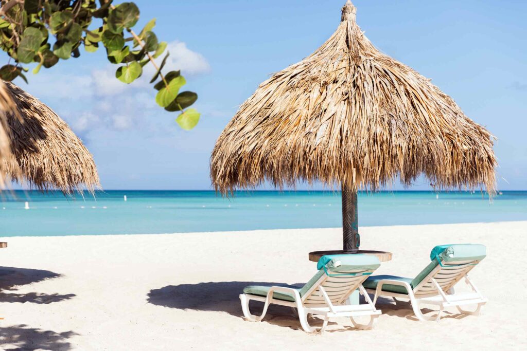 Beachside loungers beneath a thatched parasol in the Caribbean