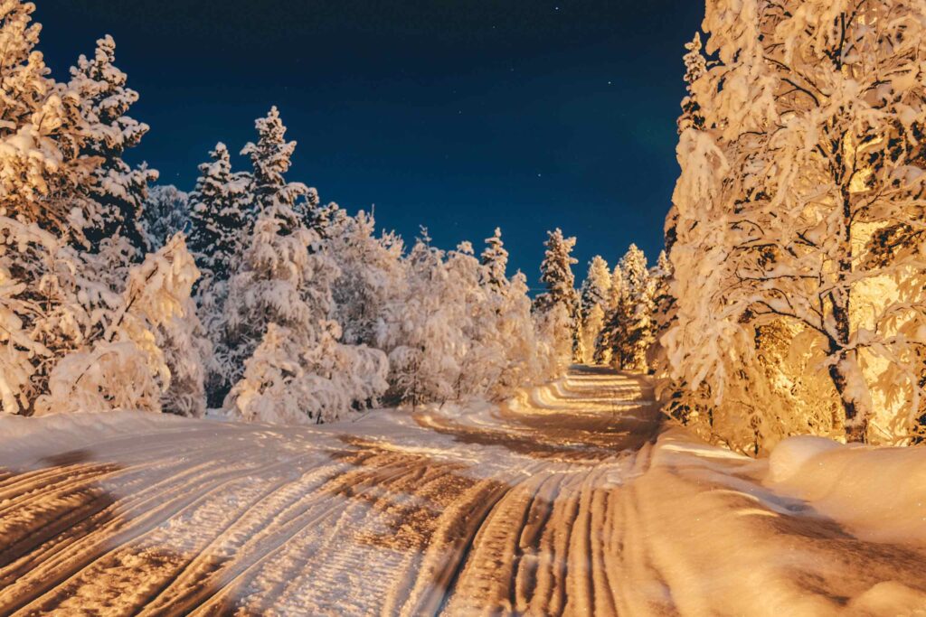 A warmly lit, snowy landscape in Finnish Lapland at night