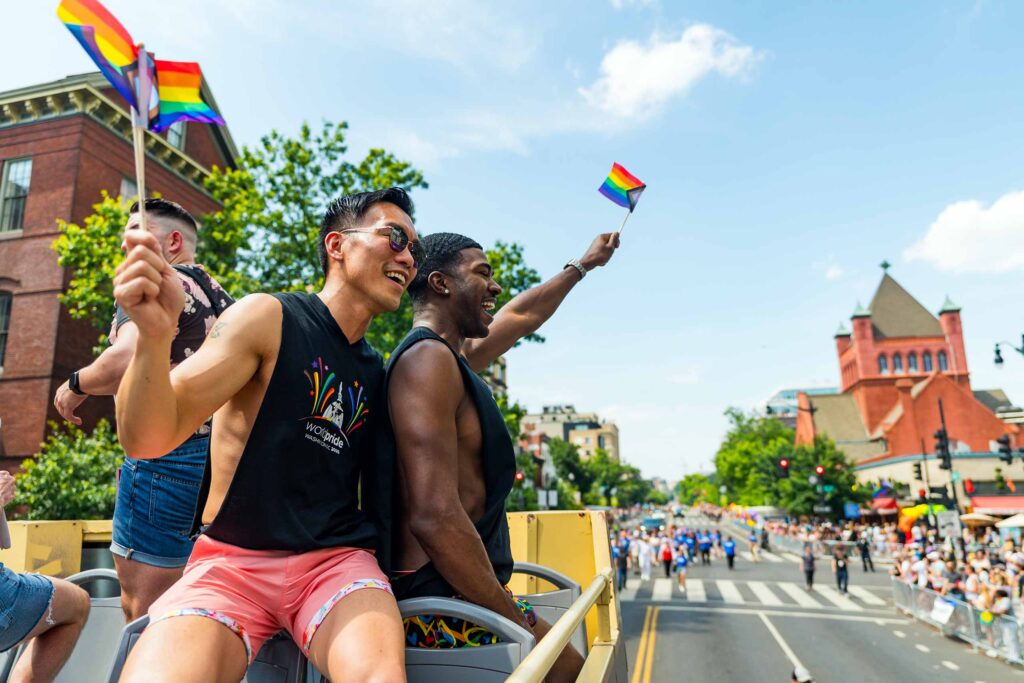 A gay couple with rainbow flags during Washington D.C. Pride, USA, an answer to the question of where to travel in 2025